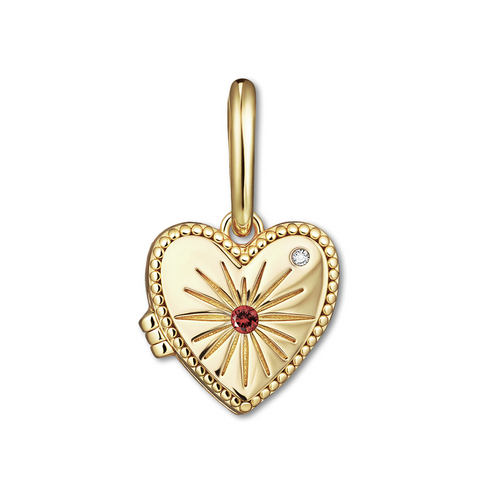 Gold heart-shaped locket with sunburst design and red gemstone on a white background
